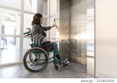 Female entrepreneur with disabilities in wheel chair waiting for elevator in office at work Female entrepreneur with disabilities in wheel chair waiting for elevator in office at work 122402410