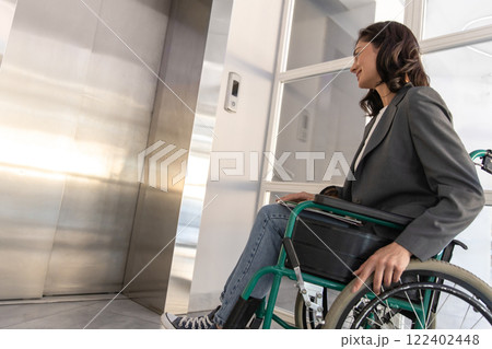 Businesswoman in wheelchair in corporate office waiting the lift Businesswoman in wheelchair in corporate office waiting the lift 122402448