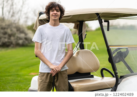 Confident young golfer near the golf cart looking determined Confident young golfer near the golf cart looking determined 122402489