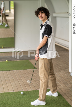 Dark-haired caucasian young golfer with a brassie in hand Dark-haired caucasian young golfer with a brassie in hand 122402726