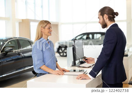 Blonde female client buying a new car and paying by card Blonde female client buying a new car and paying by card 122402738