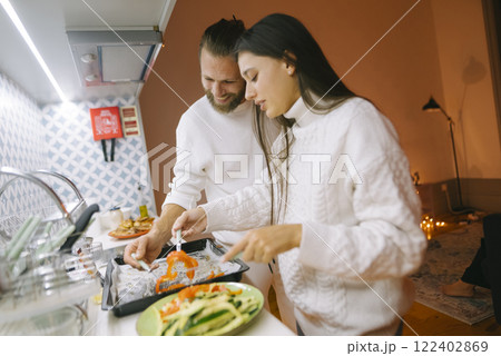 A couple is happily cooking together in a warm and inviting kitchen that is filled with love 122402869