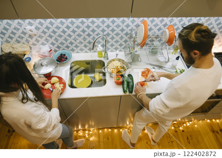 A happy couple is joyfully cooking together in their cozy and inviting kitchen space 122402872