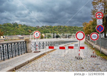 Road signs indicating that entry to the embankment is prohibited. Flood in Prague. View of Bridge over the flooding river Vltava, Prague Road signs indicating that entry to the embankment is prohibited. Flood in Prague. View of Bridge over the flooding river Vltava, Prague 122403036