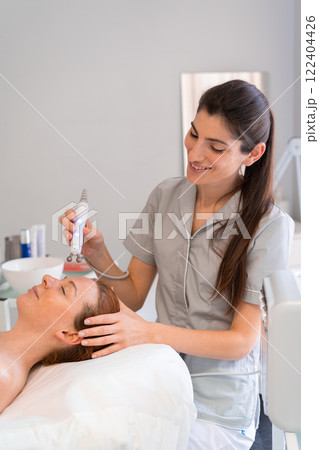 Happy cosmetologist applying iontophoresis on Happy cosmetologist applying iontophoresis on 122404426