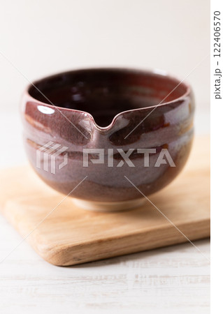 Japanese tea bowl glazed with red color on white wooden table. Japanese tea bowl glazed with red color on white wooden table. 122406570