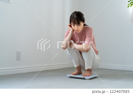 体重計に乗ってがっかりする女性 122407085