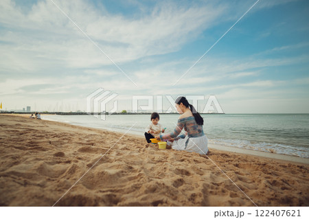 happy toddler baby girl playing sand toy with mother on sea beach in Pattaya, Thailand 122407621