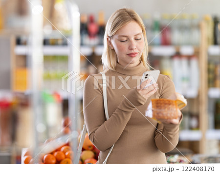 Girl scan QR code, take reading cheese label using phone camera in shop Girl scan QR code, take reading cheese label using phone camera in shop 122408170