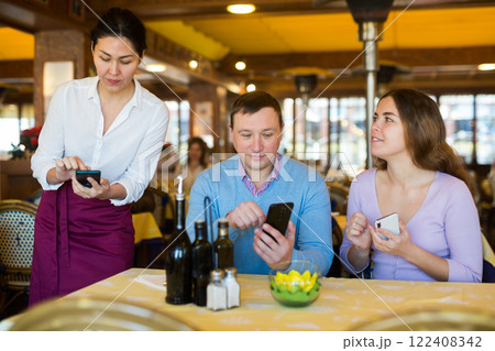 Couple using smartphones to order food in restaurant Couple using smartphones to order food in restaurant 122408342