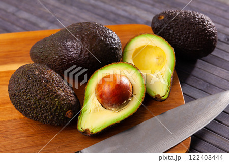 Whole and halved fresh avocados on wooden surface Whole and halved fresh avocados on wooden surface 122408444