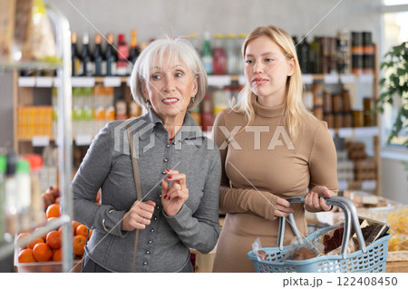 In store, young woman with grandma looking for something on shelf of showcase 122408450