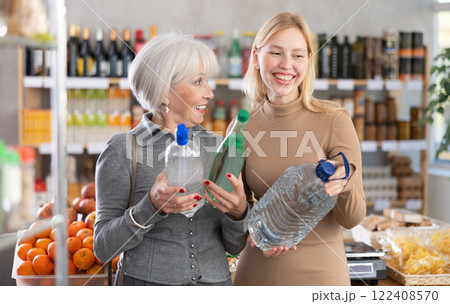 Mature mother and adult daughter buy bottles of spring water at supermarket Mature mother and adult daughter buy bottles of spring water at supermarket 122408570