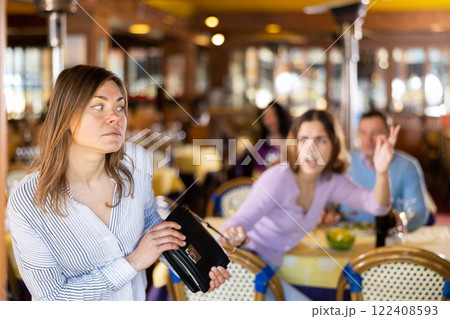 Female thief stealing handbag of frightened woman in restaurant 122408593