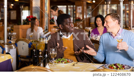 Two cheerful men having dinner in cozy restaurant Two cheerful men having dinner in cozy restaurant 122408670