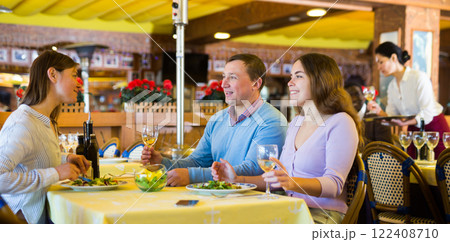 Man and two women eating and chatting in restaurant 122408710