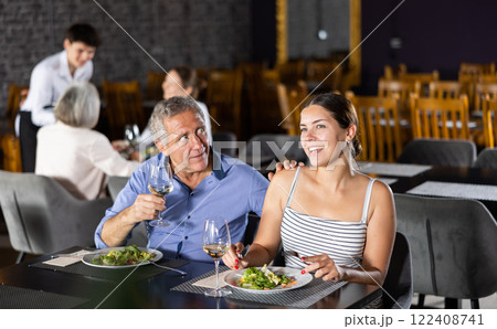 Elderly man and young woman having dinner in restaurant 122408741