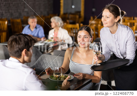 Waitress serves order of wine and wishes visitors young couple pleasant appetite and good time 122408770