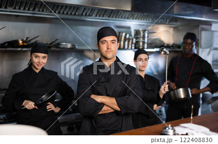 Portrait of team of cooks led by male chef in restaurant kitchen Portrait of team of cooks led by male chef in restaurant kitchen 122408830