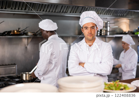 Focused man chef posing in restaurant kitchen Focused man chef posing in restaurant kitchen 122408836