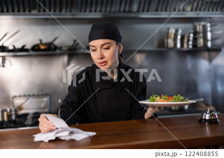 Woman cook checks paid check and cooked dish in kitchen Woman cook checks paid check and cooked dish in kitchen 122408855