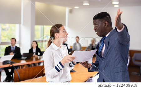 Middle aged african male boss dismissing young white female employee Middle aged african male boss dismissing young white female employee 122408919