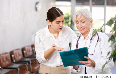 Attentive senior female doctor prescribing tests to patient of clinic to check state of health 122408941