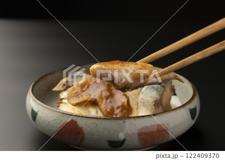 皿に盛り付けた鯖の味噌煮を箸で持ち上げる 122409370