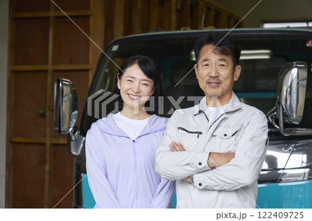 トラックの前に立つ作業員の夫婦のポートレート カメラ目線 トラックの前に立つ作業員の夫婦のポートレート カメラ目線 122409725