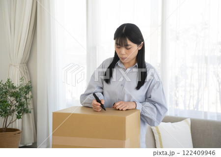 段ボール箱にマジックで書く女性 122409946