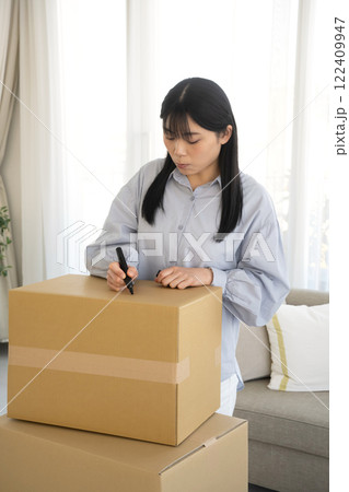 段ボール箱にマジックで書く女性 122409947
