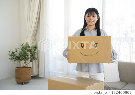 段ボール箱に笑顔のイラストを書いた箱を持つ女性 122409965