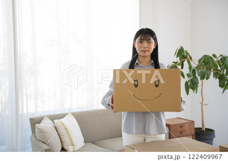 段ボール箱に笑顔のイラストを書いた箱を持つ女性 122409967