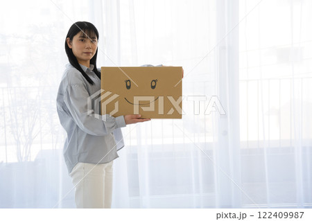 段ボール箱に笑顔のイラストを書いた箱を持つ女性 122409987