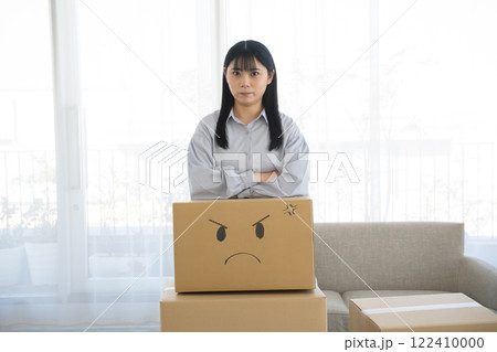 段ボール箱に顔の絵を描いて肘をつく女性 122410000