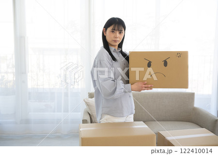 顔のイラスト絵を描いた段ボール箱を持つ女性 122410014