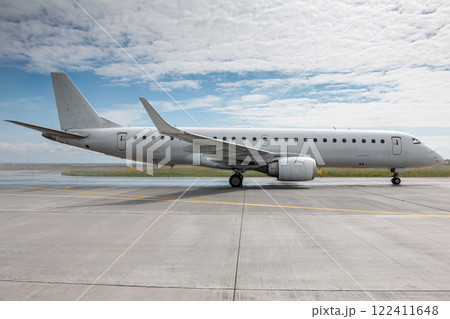 White passenger airplane taxiing on the taxiway at the airport White passenger airplane taxiing on the taxiway at the airport 122411648