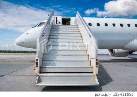 White passenger jetliner with a boarding stairs on the airport apron White passenger jetliner with a boarding stairs on the airport apron 122411659