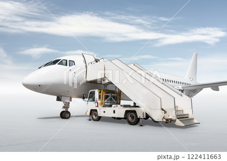 White passenger airliner with a boarding stairs isolated on bright background with sky White passenger airliner with a boarding stairs isolated on bright background with sky 122411663