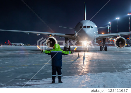 Airliner marshalling at the aiport apron at winter night. Passenger aircraft meeting 122411687