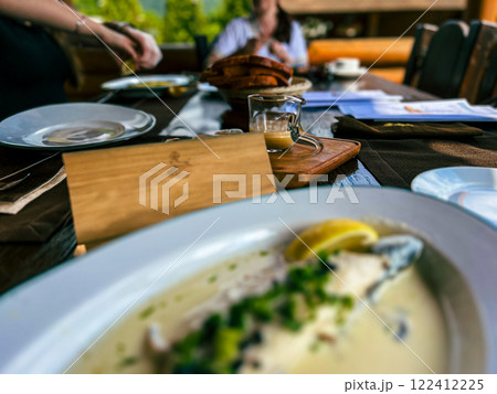 Fried Golden trout fish with lemon and herbs in a white plate on a wooden table at the restaurant in Ukraine 122412225