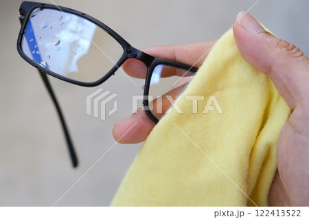 The white man's hands cleaned his glasses with a clean cloth. 122413522