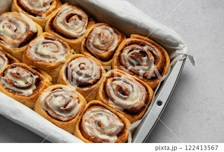 Freshly baked cinnamon rolls drizzled with icing in a baking pan 122413567
