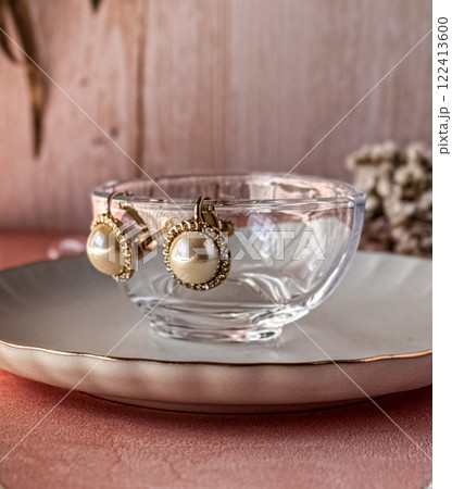 テーブルに置いたガラスの器のふちにかけられたパールのイアリング 122413600