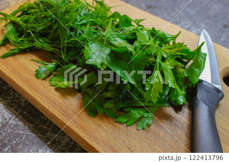 Chopped greenery on wooden board. Bunch of dill and parsley on cutting board with knife. Vegan diet concept. Healthy food. Fresh herbs on wooden chopping board. Chopped greenery on wooden board. Bunch of dill and parsley on cutting board with knife. Vegan diet concept. Healthy food. Fresh herbs on wooden chopping board. 122413796