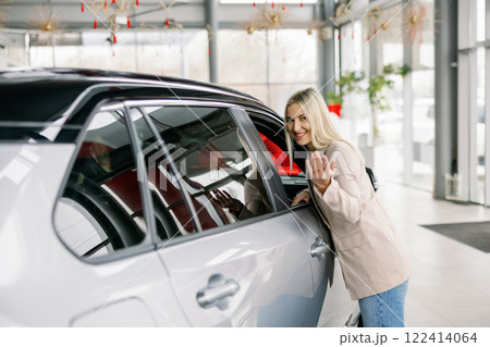 Saleswoman inviting to enter new car in dealership Saleswoman inviting to enter new car in dealership 122414064