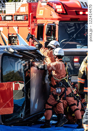 出初式の消防訓練で事故で横転した自動車のルーフを油圧カッターで切断する救助訓練を行うレスキュー隊員 122414470