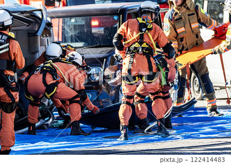 出初式の消防訓練で事故で横転した自動車のルーフを油圧カッターで切断する救助訓練を行うレスキュー隊員 出初式の消防訓練で事故で横転した自動車のルーフを油圧カッターで切断する救助訓練を行うレスキュー隊員 122414483