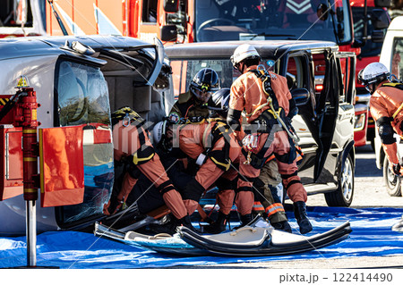 出初式の消防訓練で事故で横転した自動車のルーフを油圧カッターで切断する救助訓練を行うレスキュー隊員 出初式の消防訓練で事故で横転した自動車のルーフを油圧カッターで切断する救助訓練を行うレスキュー隊員 122414490