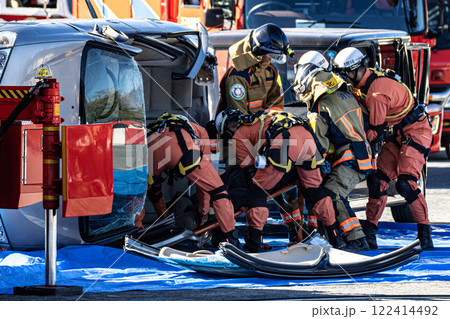 出初式の消防訓練で事故で横転した自動車のルーフを油圧カッターで切断する救助訓練を行うレスキュー隊員 出初式の消防訓練で事故で横転した自動車のルーフを油圧カッターで切断する救助訓練を行うレスキュー隊員 122414492